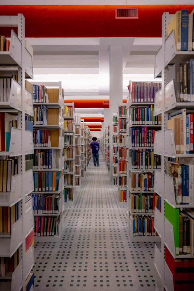 a man walking through a library filled with lots of books