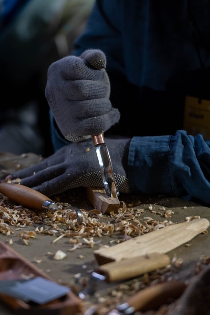 Hands carving wood with chisels and shavings